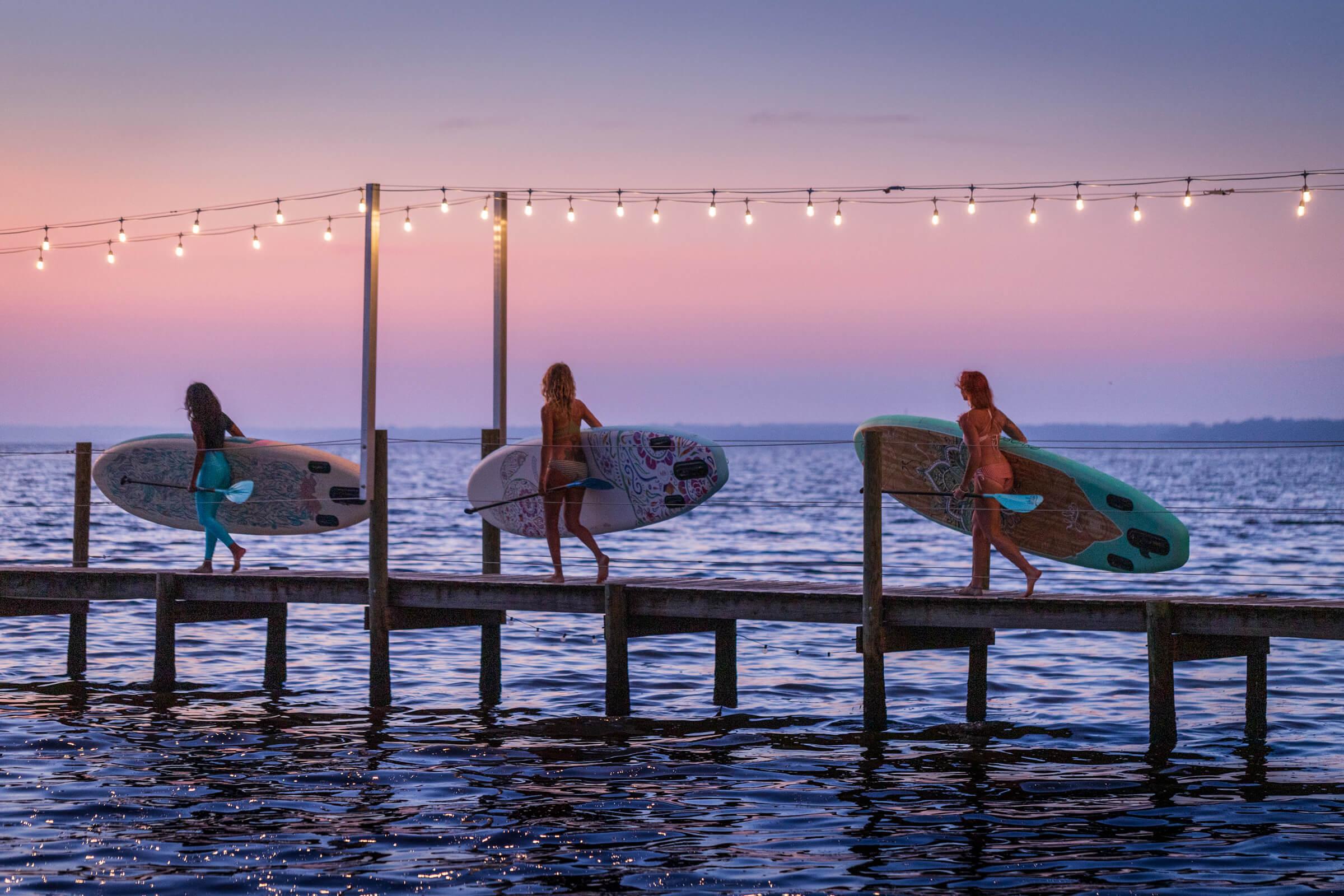 Yolo Board | Three Women Carrying Sups On Pier